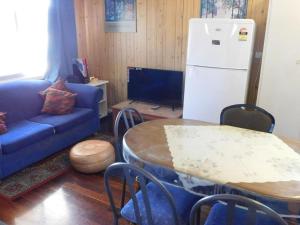 a living room with a blue couch and a table and a refrigerator at Cottage 57 - Topspot Cottages in Jurien Bay