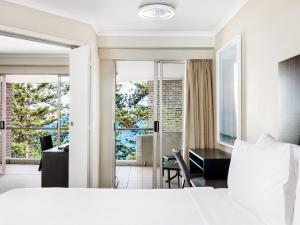 a bedroom with a bed and a desk and a room at Quest Manly in Sydney