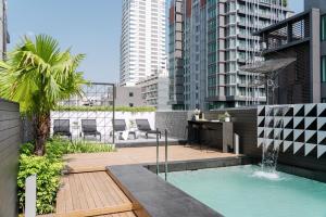 a patio with a swimming pool with chairs and a fountain at Citichic Sukhumvit 13 by Compass Hospitality in Bangkok