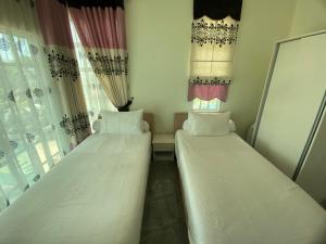 two beds in a small room with windows at Che Beach House in Marang