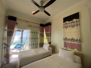 a bedroom with two beds and a ceiling fan at Che Beach House in Marang