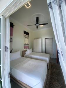 two beds in a bedroom with a ceiling fan at Che Beach House in Marang