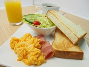 a plate of breakfast food with eggs toast and a cup of juice at i RESORT ARTIA Sensual Gifu (Adult Only) in Ginan