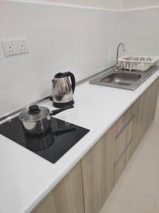 Una encimera de cocina con una estufa y un fregadero. en Homestay KLIA Core Soho Suites, en Sepang