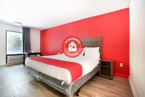 OYO Hotel Decatur I-285 The Perimeter في ديكاتور: غرفة نوم حمراء مع سرير كبير بجدار احمر