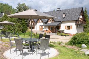 a table and chairs with an umbrella in front of a house at Beskid Ski Villa in Wisła