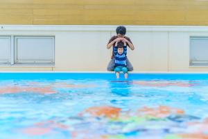 a young boy sitting on the edge of a swimming pool at Hotel Ocean (Kokusai-Dori) in Naha