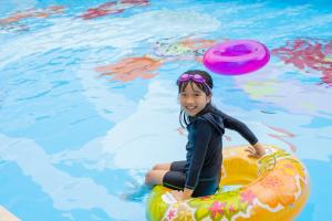 a young girl sitting on an inflatable raft in a pool at Hotel Ocean (Kokusai-Dori) in Naha