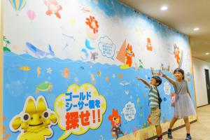 a boy and a girl standing in front of a wall with a mural at Hotel Ocean (Kokusai-Dori) in Naha