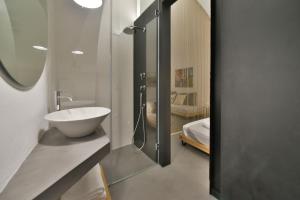 un bagno con lavandino e porta doccia in vetro di Voltabianca Suite a Ostuni