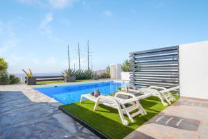 a swimming pool with two lounge chairs next to a house at Casa Amanecer 2 in Mácher