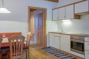 cocina con armarios blancos, mesa y comedor en Wieserhof - Apartment Benjamin, en Valles