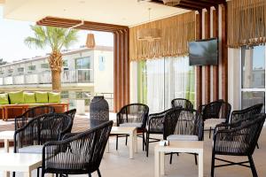 a restaurant with tables and chairs and a tv at Sunprime Ayia Napa Suites - Adults Only in Ayia Napa