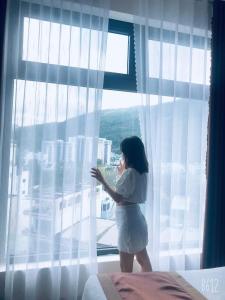 a woman standing in front of a window at Khách sạn Misa in Quy Nhon