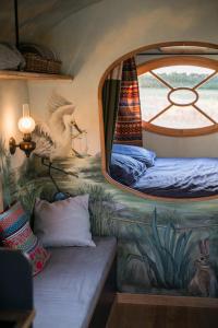 ein Schlafzimmer mit einem Bett in einem Zimmer mit einem Fenster in der Unterkunft La Roulotte des Grillots in Beaulon