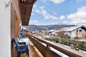 balcón con mesa, sillas y vistas en Ferienwohnungen Holzner groß en Inzell