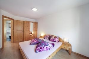 a bedroom with a large white bed with purple pillows at Strickerhof - Appartment 2 in Saltusio