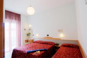 a bedroom with two red beds and a window at Hotel Hamilton in Misano Adriatico