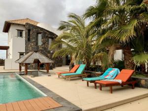 a group of lounge chairs next to a swimming pool at Villa Annunaki in Lajares