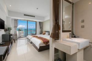 a bedroom with a bed and a bathroom with a sink at Sanya Sun and Sea Gueshouse in Sanya