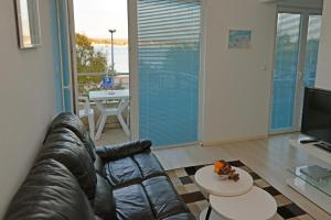 a living room with a leather couch and a table at Apartman Lunga, Murter in Murter