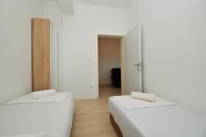 two beds in a room with white walls and wooden floors at Apartman Lunga, Murter in Murter