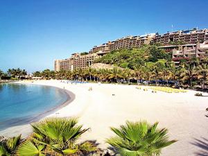 a beach with palm trees and a resort at Guesthouse Le Rêve in Mogán