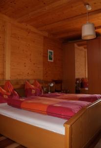 Cama grande en habitación con paredes de madera en Verleierhof, en Castelrotto