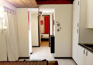 une cuisine avec des placards blancs et un couloir dans l'établissement BnButler - Navigli Apartment - Vicolo Lavandai, à Milan