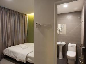 a bathroom with a bed and a toilet and a sink at Econtel Queensbay in Bayan Lepas