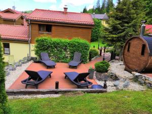 a patio with chairs and a barrel in front of a house at Penzión Pod Guglom in Mlynky 