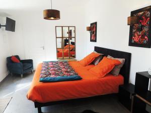 Una cama con una manta naranja encima. en Laubertière, en Marennes