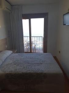 a bedroom with a bed with a view of a balcony at Hotel Condestable in Benidorm