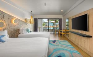 
a hotel room with a bed, television, and couch at LIV Hotel Phuket Patong Beachfront - SHA Extra Plus in Patong Beach
