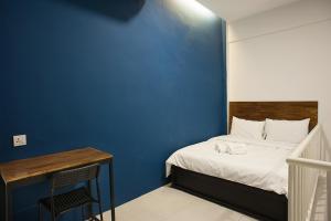 een slaapkamer met een blauwe muur en een bed en een bureau bij Econtel Queensbay in Bayan Lepas