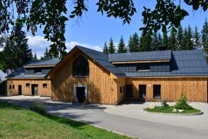 a large wooden barn with a black roof at Montanie Resort in Desná