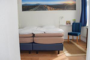 ハーネンクレー・ボックスヴィーゼにあるHenne Hahnenkleeのベッドと青い椅子が備わる客室です。