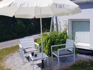 zwei Stühle und ein Regenschirm vor einem Haus in der Unterkunft Apartment Mai in Elmenhorst