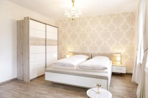 a bedroom with a white bed and a chandelier at Landgasthof Deutsches Haus in Hüttenrode