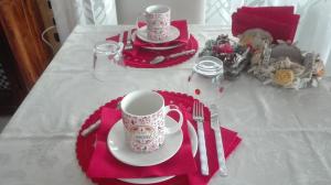 een tafel met een rood servet en een kopje, vork en mes bij B&B Villa Anita in Bellano