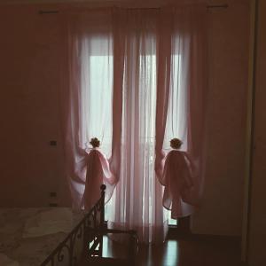 een slaapkamer met 2 roze gordijnen en een bed bij B&B Villa Anita in Bellano