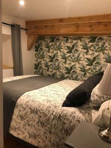 sypialnia z dużym łóżkiem z zagłówkiem kwiatowym w obiekcie Les Gîtes du Racème w mieście Blienschwiller