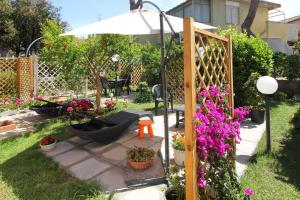フォッローニカにあるHoliday Home Arzilliのハンモックと花、傘が備わる庭園