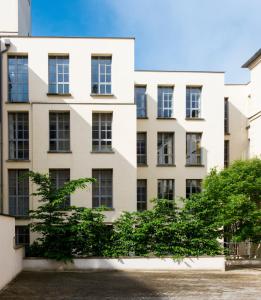 un immeuble d'appartements avec un arbre en face de celui-ci dans l'établissement Appartements - Le Logis Versaillais, à Versailles