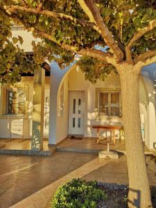 a tree in front of a house with a table at Haraki Village in Haraki