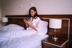 a woman sitting on a bed with a pillow at Hotel Dębowiec in Bielsko-Biala