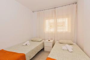Duas camas num quarto com paredes brancas e uma janela em Panoramic View em Los Abrigos