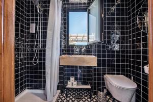 a black tiled bathroom with a sink and a toilet at Lemon Tree Stay in Faro
