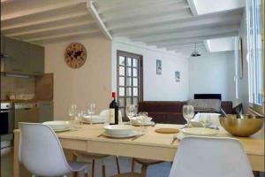 einen Esstisch mit weißen Stühlen und eine Flasche Wein in der Unterkunft Cauterets T2 coeur village in Cauterets