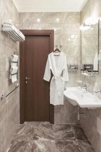 a bathroom with a sink and a white shirt on a door at Petr Hotel in Saint Petersburg